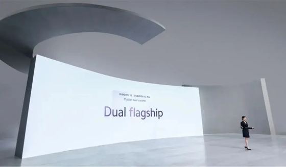 Xiaomi 12 / Xiaomi 12 Pro (small, on screen) booth — Screen prints 'Xiaomi 12 · Xiaomi 12 Pro / Master every scene / Dual flagship'; ctx names the Xiaomi 12 Series overseas online launch (ctx also lists 2022 MWC Barcelona separately — not what the frame shows)